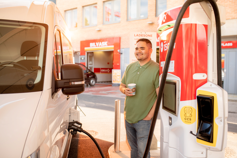 En mann som lader varebilen på en Circle K stasjon