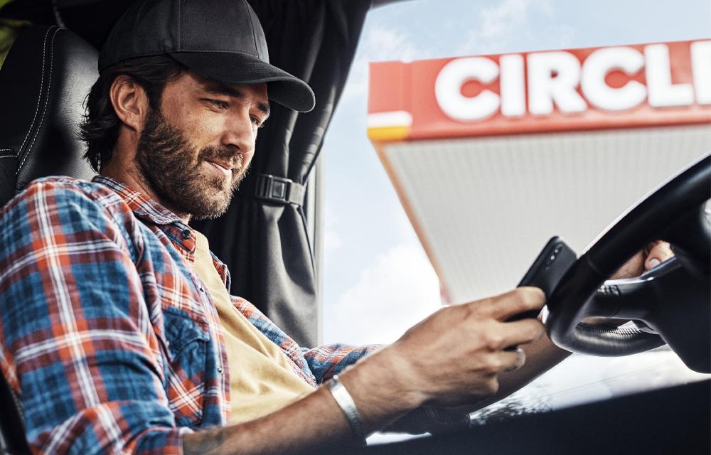 Lastebilsjåfør med mobil på stasjon
