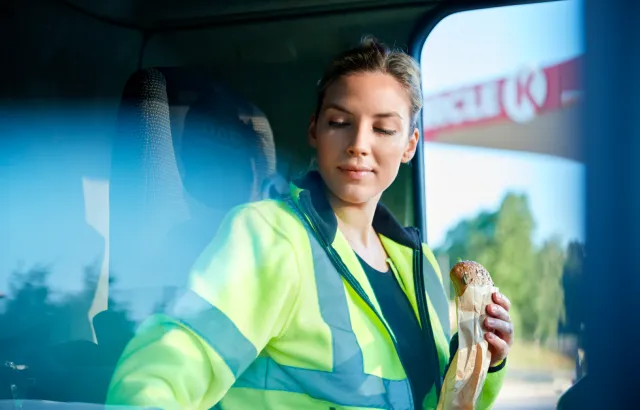 Truck driver sitting in her truck with a Circle K sandwich in hand