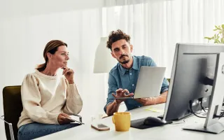 2 personer diskuterer foran pc