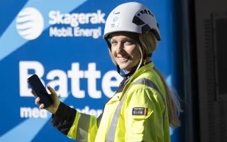 Dame med mobil foran batteri