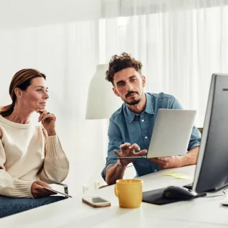 2 personer diskuterer foran pc