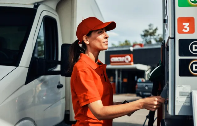 Dame foran bensinpumpe på bensinstasjon